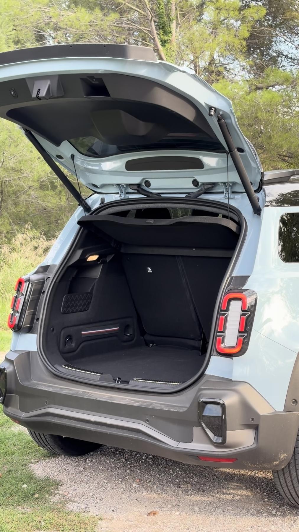 Maletero abierto del Renault 4 E-Tech azul claro, con la bandeja trasera y un pequeño doble fondo