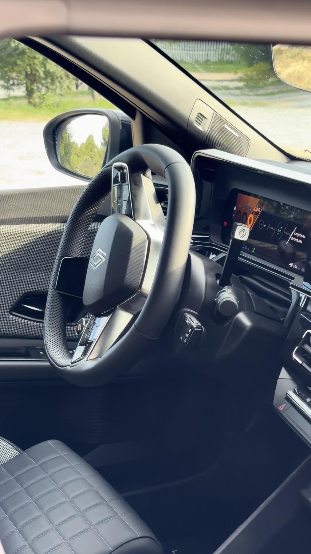 Volante del Renault 4 E-Tech con el cuadro de instrumentos digital y la palanca de la columna de dirección, y un asiento de cuero acolchado con costuras