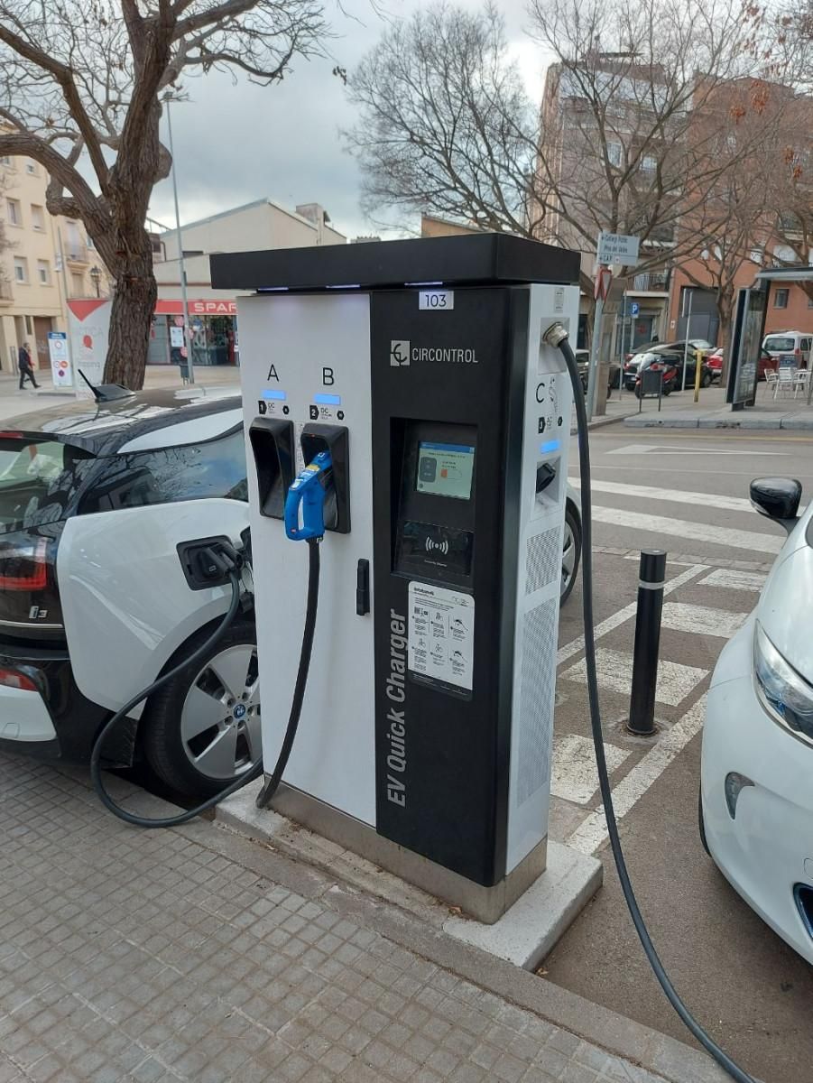Cargador rápido con conectores A, B y C y un BMW i3 enchufado en la calle de la Mina